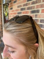 A woman with long blonde hair wearing sunglasses.