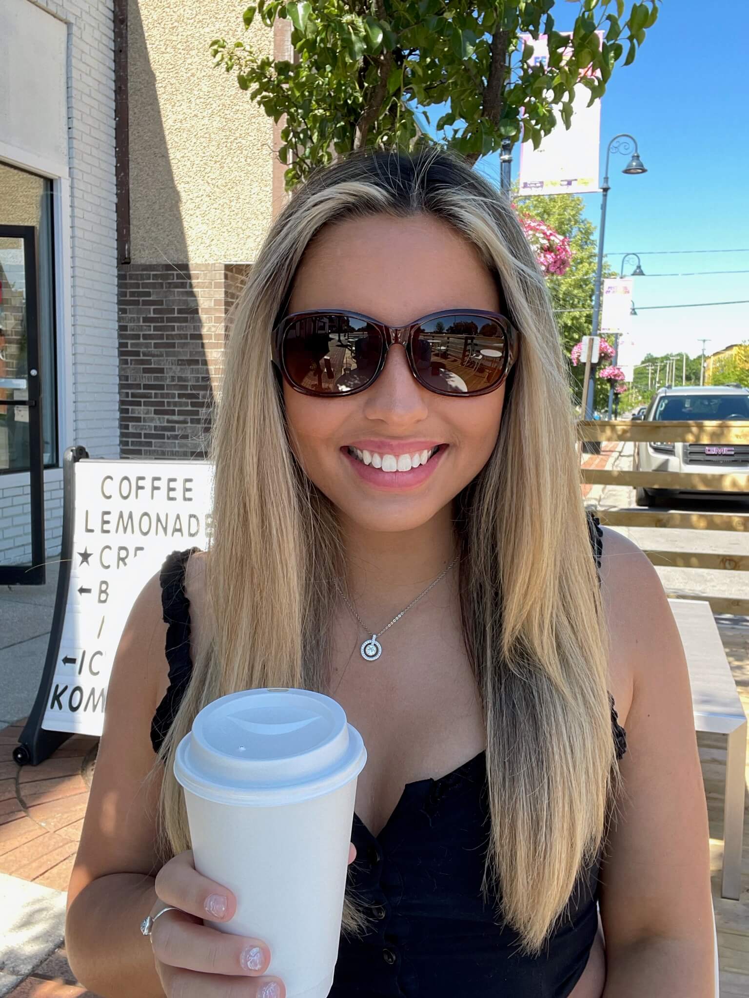Woman wearing shades and holding coffee cup