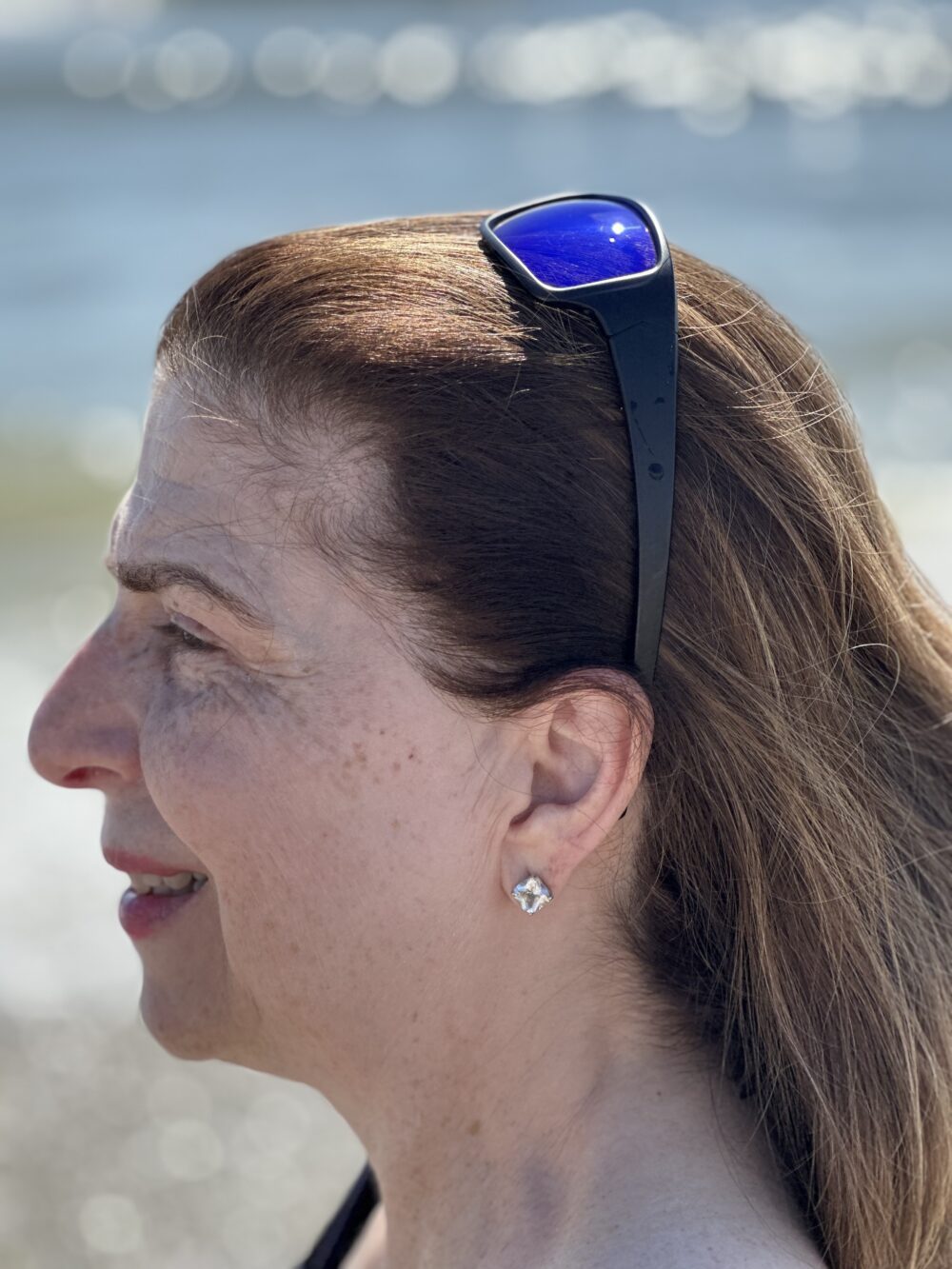 Profile of a woman with sunglasses on her head near the sea.